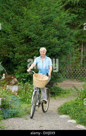 Senior woman riding bicycle in park Stock Photo