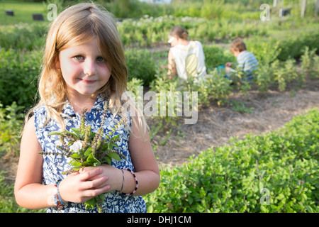 Portrait of girl holding bunch of foliage on herb farm Stock Photo