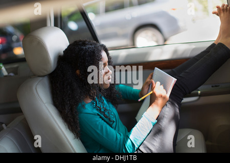 Young girl in car doing homework Stock Photo