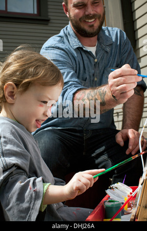 Father and daughter outdoors painting on easel Stock Photo