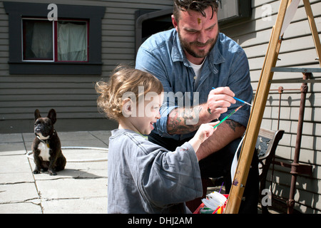 Father and daughter outdoors painting on easel Stock Photo