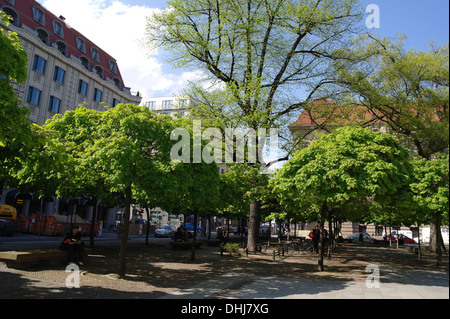 Blue sky view four people sitting talking reading below green trees shade, Charlottenstrasse to Franzosische Strasse, Berlin Stock Photo