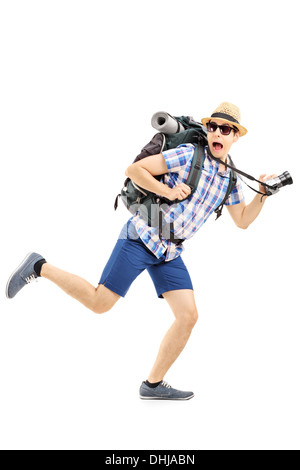 Full length portrait of a scared hiker with backpack and camera running away Stock Photo