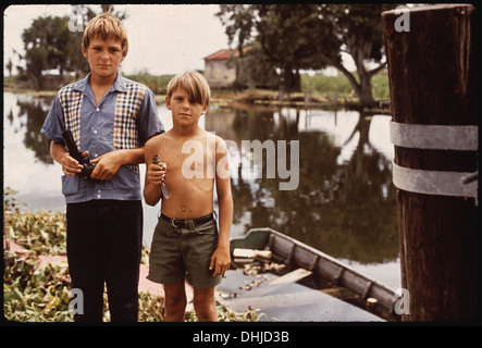 Boys from a fisherman’s family in Bayou Gauche, Louisiana, are pictured with an airgun and a bird, symbolizing rural life and outdoor traditions in the wetlands. Stock Photo