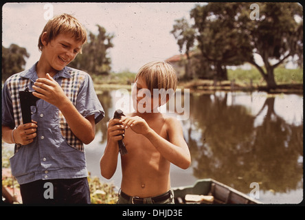 BOYS WITH AIRGUN AND BIRD. THESE FISHERMAN'S SONS LIVE IN BAYOU GAUCHE, DEEP IN THE WETLANDS OF LOUISIANA 211 Stock Photo