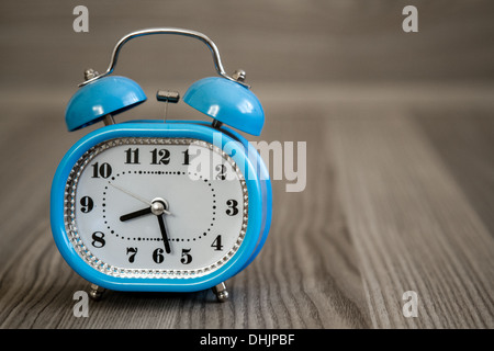 Retro alarm clock on wooden table and in front of wooden background Stock Photo