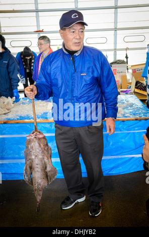 Catch of the day: Fisherman or fishmonger holding large fish at a fish market Stock Photo
