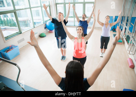 Young people with hands in the air in a yoga class Stock Photo