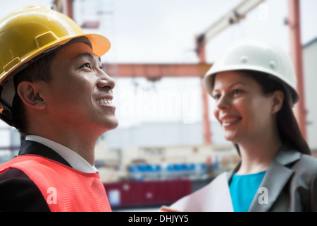 Two engineers smiling in protective workwear outside in a shipping yard Stock Photo