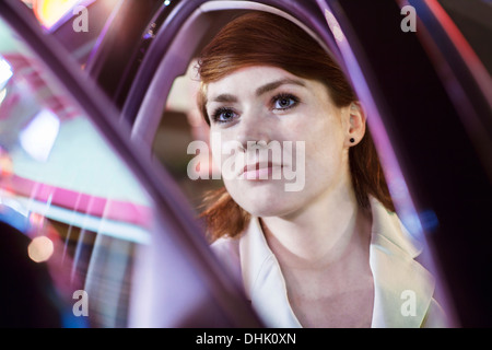 Serene businesswoman opening car door at night, close-up, reflected lights Stock Photo