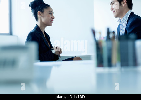 Two colleges smiling and talking by the desk in the office Stock Photo