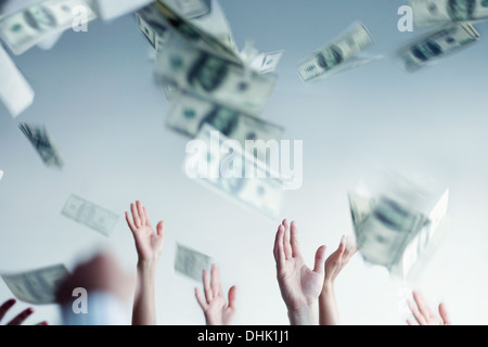 Close up on hands raised throwing and catching money in the air Stock Photo