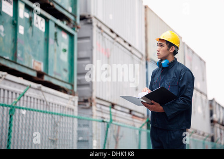 Young worker in protective work wear examining cargo in a shipping yard Stock Photo