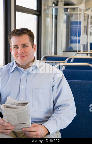 Man on train with newspaper Stock Photo