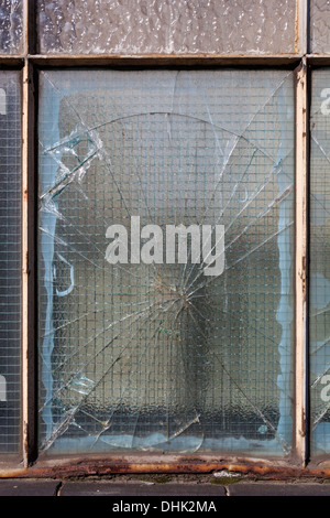Close-up of a rusty metal framed window with smashed wired glass. Stock Photo
