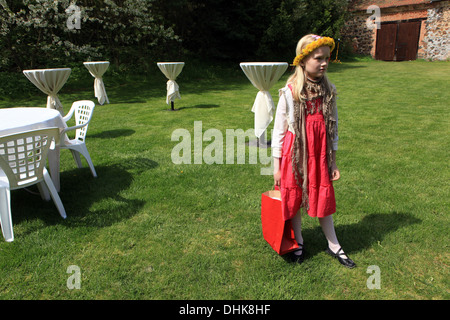 Little girl with dandelion wreath, garden with white tables Stock Photo