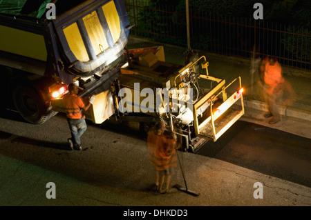 road workers at night resurfacing road Stock Photo