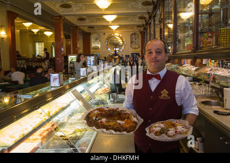Waiter with traditional Bolo Rei cakes at Pastelaria Versailles cafe and bakery in Saldanha district, Lisbon, Lisboa, Portugal Stock Photo