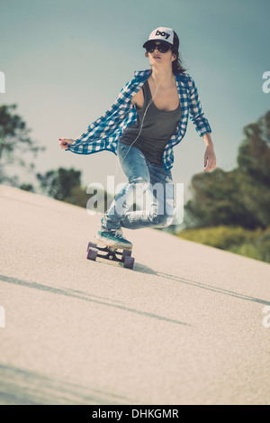 Young woman down the road with a skateboard Stock Photo