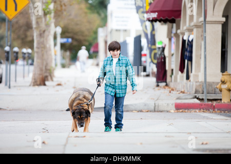 A 10 year old boy and his dog walking down the sidewalk Stock Photo