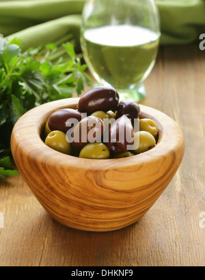 marinated green and black olives (Kalamata) in a wooden bowl Stock Photo