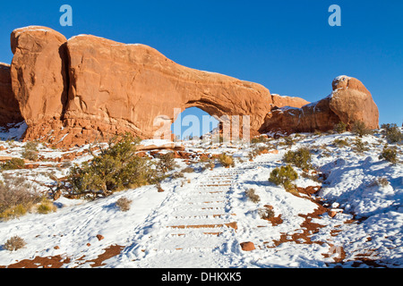 Snow-covered stairs on the trail to the wolf-like South Window Arch rock formation in Arches National Park, Utah Stock Photo