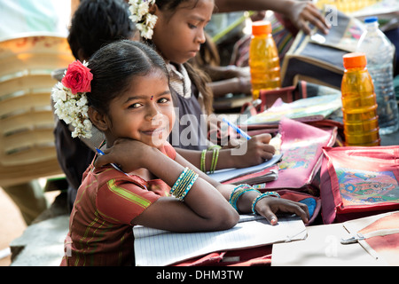 Rural Indian village school girls writing in books in an outside class. Andhra Pradesh, India, selective focus. Stock Photo
