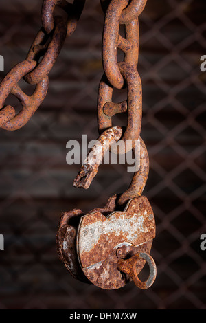 Big old rusty metal open padlock with a key hanging on a bold chain Stock Photo