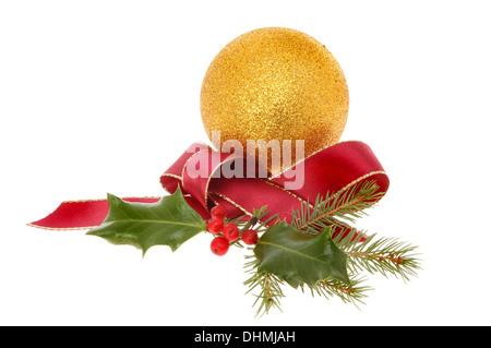 Christmas decoration a gold glitter bauble with red ribbon and seasonal foliage isolated against white Stock Photo