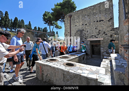 Tourists looking round The Grande Taberna, an Roman ancient pub with marble counters selling food and drink Stock Photo