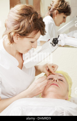 Beautician does eyebrows tweezing procedure Stock Photo