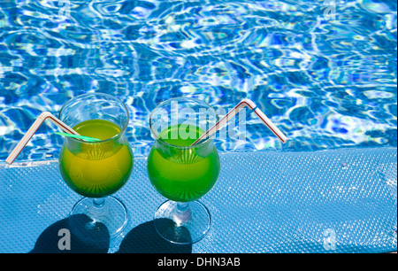 Glasses stand with cocktail on edge of pool Stock Photo
