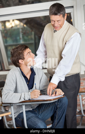 Professor Explaining Exam To Student In Classroom Stock Photo