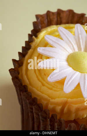 half of lemon daisy cupcake on pale yellow background Stock Photo