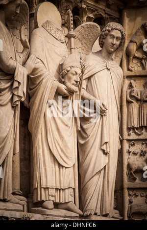 Saint Denis - holding his own head, statue on the front facade of Cathedral Notre Dame, Paris France Stock Photo