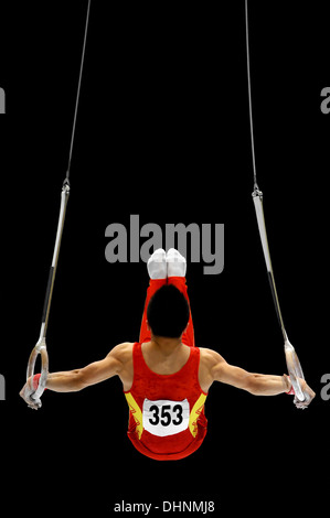 Back view with a gymnast performing on the rings apparatus Stock Photo