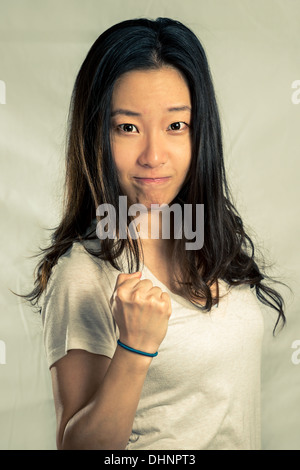 Young woman clenching her fist for encouragement, with fashion tone and background Stock Photo