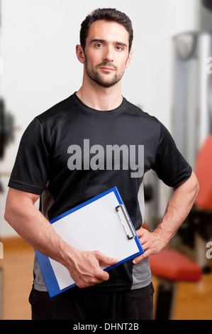 Personal Trainer, with a pad in his hand, in a gym Stock Photo