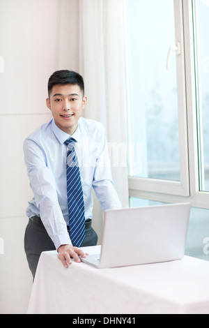 Businessman standing, holding a laptop, smiling Stock Photo