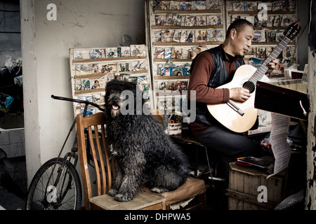 Shop worker and dog play their music to the street from their record shop, welcoming the customers in with melody's. Stock Photo