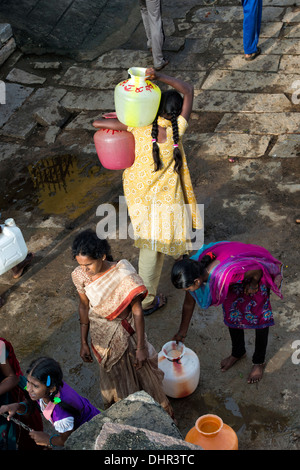Indian teenage girl carrying water pots away from a well in a rural Indian village street. Andhra Pradesh, India Stock Photo