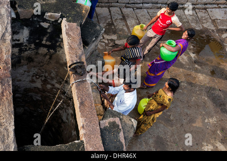 Indian women and men drawing water from a well in a rural Indian village street. Andhra Pradesh, India Stock Photo
