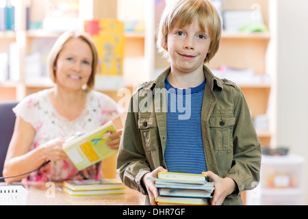 Boy Checking Out Books From Library Stock Photo