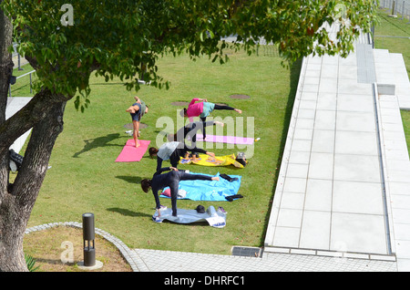 A teacher and four students doing yoga in a park. Stock Photo