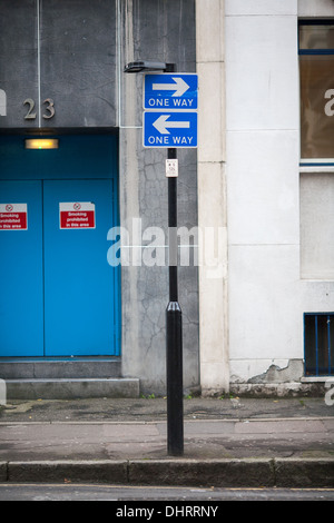 Two one-way traffic signs mounted one above the other but both pointing in opposite directions. London, UK. Stock Photo