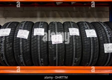 Row of new summer tires for cars stored on shelf in workshop of tire center Stock Photo