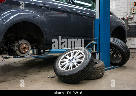 Changing summer tyres and mounting winter tires on wheels of car on ramp in assembly workshop of tyre centre Stock Photo