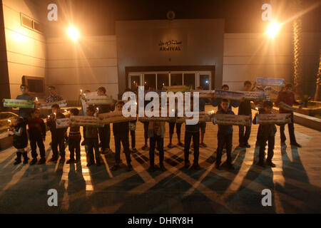 Nov. 14, 2013 - Rafah, Gaza Strip, Palestinian Territory - Palestinian children hold placards beside the remains of the car that late Hamas military commander Ahmed al-Jaabari was riding in when he was killed in an Israeli air strike, during the first anniversary of his death, at Rafah Crossing in the southern Gaza Strip, November 14, 2013. al-Jaabari was killed by an Israeli military strike while driving along Omar Mukhtar Street in Gaza City in the attack, which was a joint operation by the Shin Bet and the IDF, came amid a series of Palestinian rocket attacks against Israel and Israeli air Stock Photo