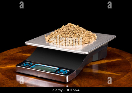 A pile of small gold nuggets on a scale being weighed for their investment value. Stock Photo