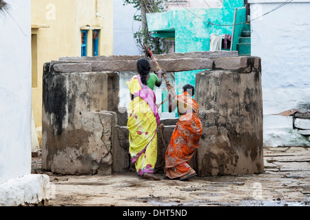 Indian women drawing water from a well in a rural Indian village street. Andhra Pradesh, India Stock Photo